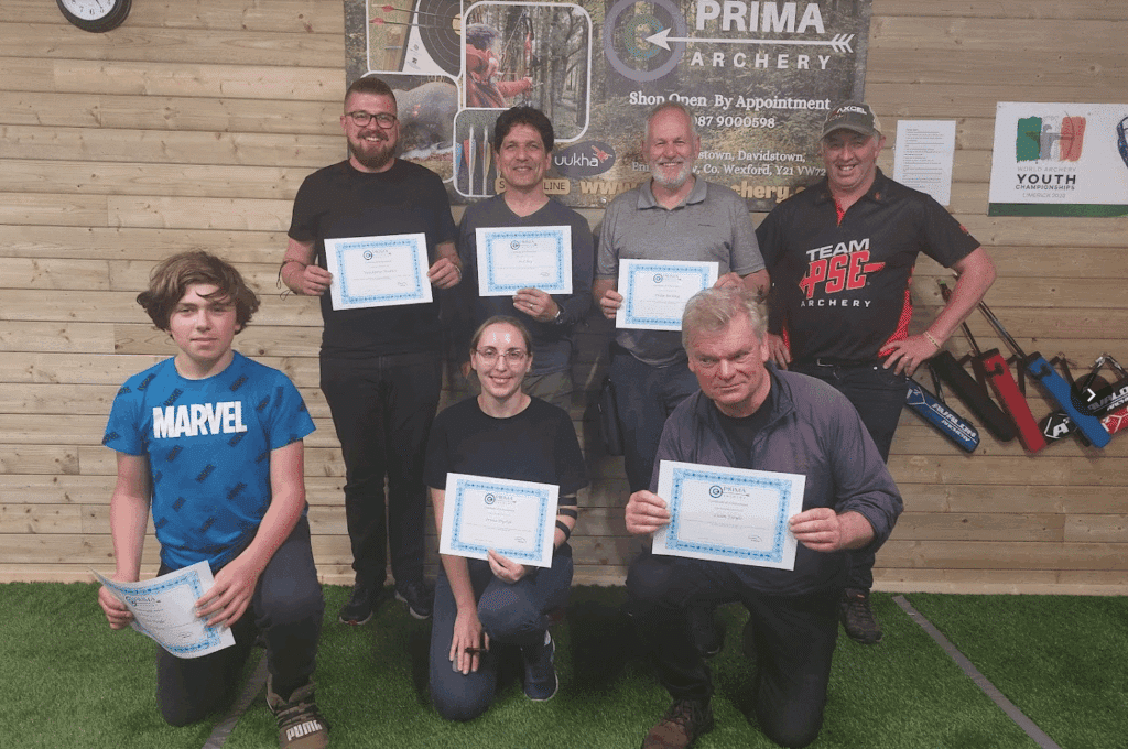 Adults displaying certificates after completing a professional archery workshop