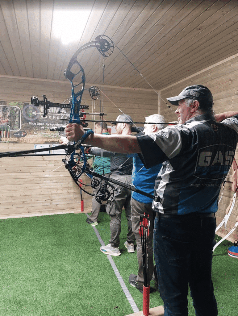A group of archers drawing a bow at an indoor target range