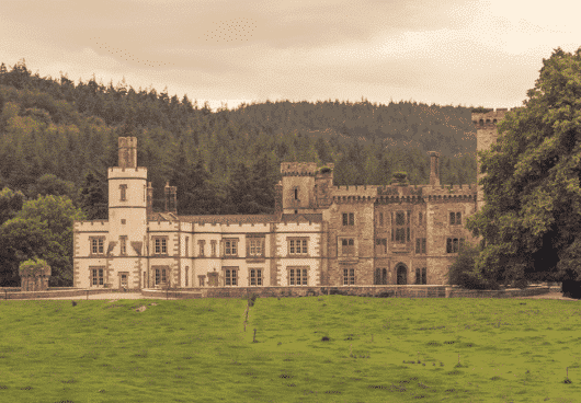Wide view of a massive historic stone estate with multiple windows and classical architecture