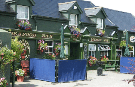 Traditional storefront with a bright blue facade, floral window boxes, and outdoor cafe seating